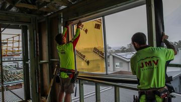 Workers install a window at a construction site