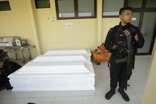 A police officer stands guard near coffins being prepared for the victims of the church bombings at the weekend. (AAP)