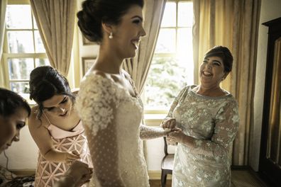 Bridesmaids and mother of the bride help bride on wedding day