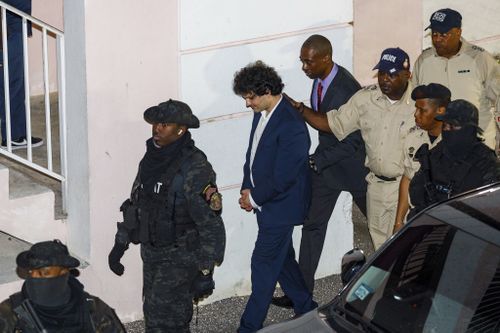 Samuel Bankman-Fried, center, is escorted out of the Magistrate Court building the day after his arrest in Nassau, Bahamas, Tuesday, Dec. 13, 2022. 