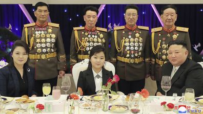 North Korean leader Kim Jong Un (right) with his wife Ri Sol Ju (left) and his daughter poses with military top officials for a photo at a feast to mark the 75th founding anniversary of the Korean Peoples Army at an unspecified place in North Korea on Tuesday.