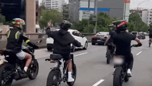 Gruppo di giovani in bici elettrica nel traffico dell'ora di punta di Sydney.