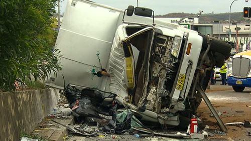 Emergency services had to cut through the nylon sides of the truck before they could access the crushed car. (9NEWS)