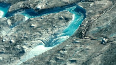 Large rivers of melting water drain into moulin holes that empty into the ocean from underneath the ice.