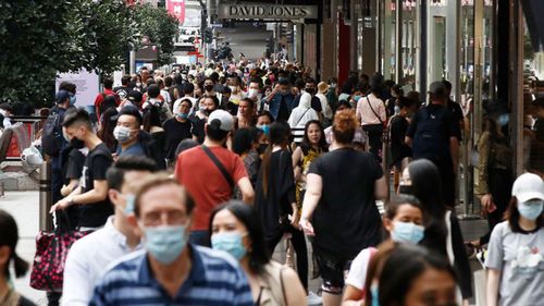 Masked pedestrians walk along a Melbourne street.