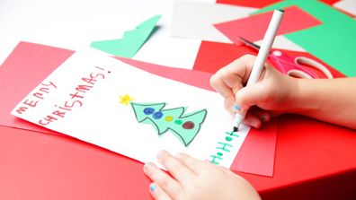 A young girl makes the finishing touches to her Christmas card.  Merry Christmas!