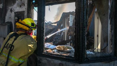 A firefighter hoses down a burning house during the Getty Fire on October 28, 2019 in Los Angeles, California.