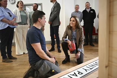 Britain's Kate, Princess of Wales, known as the Duchess of Rothesay when in Scotland, uses a nail gun as she helps to construct a sign for a Community Pantry, during a visit to Aros Hall community hub in the town of Tobermory on the Isle of Mull, Scotland, Tuesday, April 29, 2025. (Oli Scarff/PA via AP)