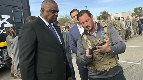 Defence Secretary Lloyd Austin takes a closer look at the device used to control a swarm of drones that lifted off from a parking area at the Defense Innovation Unit in Mountain View, Calif, on Friday, Dec. 1, 2023.  