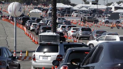 Cars wait in line as they enter a COVID-19 vaccination site at Dodger Stadium in Los Angeles.