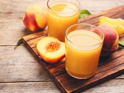 Natural peach juice and fresh fruits on wooden table. 