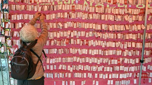 A woman attaches a name card wishing for good results for students in South Korea's college entrance exam, at a temple in Seoul on November 18, 2021.