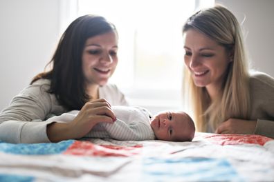The Two friend girl with a newborn baby on bed STOCK
