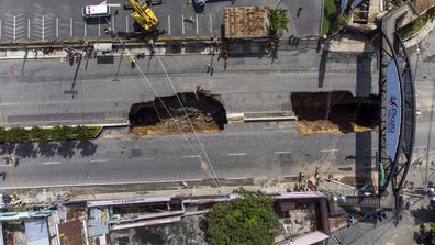 A view of a sinkhole on the main road in Villa Nueva, Guatemala, Sunday, Sept.  25, 2022. Rescuers are searching for people who are believed to have fallen into the sinkhole while driving their vehicle, while four others were rescued alive from the scene on Saturday night.  (AP Photo/Moises Castillo)