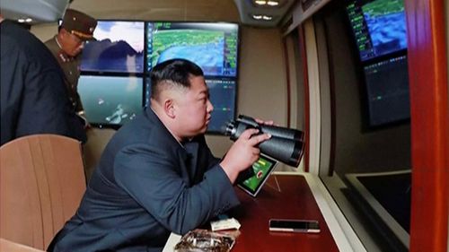 North Korean leader Kim Jong Un, equipped with binoculars, supervises a rocket launch test. 