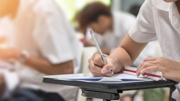 Exam at school with student&#x27;s taking educational admission test in class, thinking hard, writing answer in university classroom, education and world literacy day concept