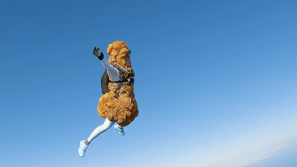 KFC&#x27;s human drumstick skydives down towards a giant delivery bag. 