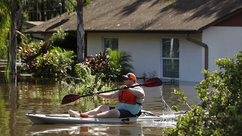 A man paddles a kayak near a flooded home in Lithia. (Associated Press)