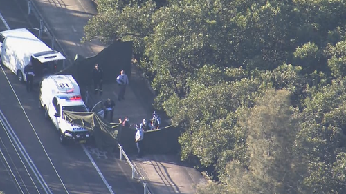 Police at the scene near a bridge on the NSW Central Coast where a woman's body was found in shallow waters.