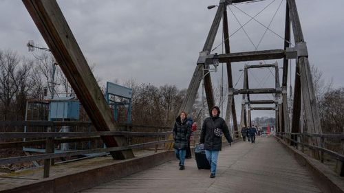 Ukrainian refugees cross the bridge spanning the Tisza river, connecting Ukraine with Romania.