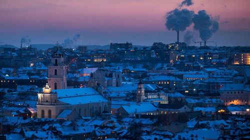 Smoke rises from chimneys during a freezing winter evening over snow covered Vilnius, Lithuania. (AP).