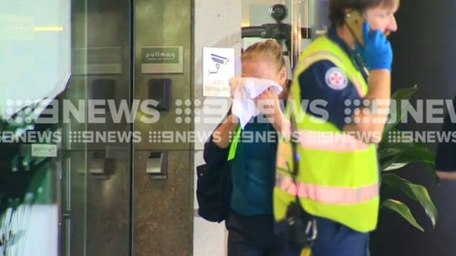 A woman emerges from the hotel covering her face, after affected levels were evacuated. (9NEWS)