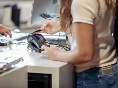 A  shot of a Middle Eastern female student buying some equipment in a store on campus.