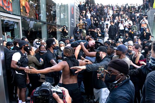 A man is lifted up by Patrick Hutchinson and taken to police lines after being beaten in clashes between protesters supporting the Black Lives Matter movement and opponents in central London, in the aftermath of the death of unarmed black man George Floyd in police custody in the US.