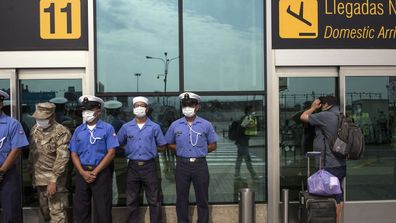 Marines stand guard as a passenger waits to reschedule a cancelled flight at a semi-closed airport, in Lima, Peru.