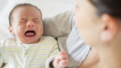 Crying baby being held by mother