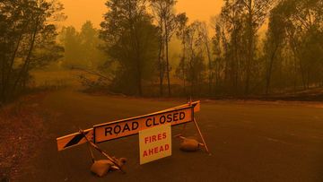 A road closure sign on the intersection of The River Road and the Kings Highway which are both closed due to the fire near Batemans Bay.