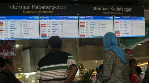 Passengers check for flight schedules at the airport in Surabaya, East Java. (Getty Images)