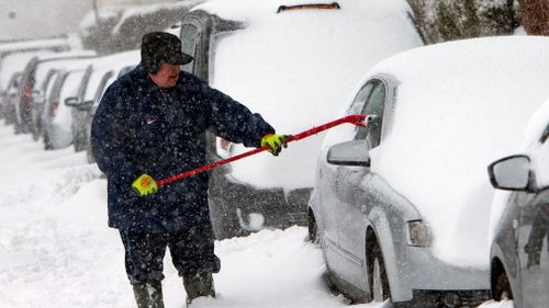 A man usues a mop to clear snow from his car in Old Drumchapel, Glasgow, Scotland. (AAP)