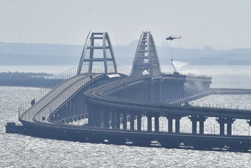 A helicopter drops water to stop fire on Crimean Bridge connecting Russian mainland and Crimean peninsula over the Kerch Strait, in Kerch, Saturday, Oct. 8, 2022. 