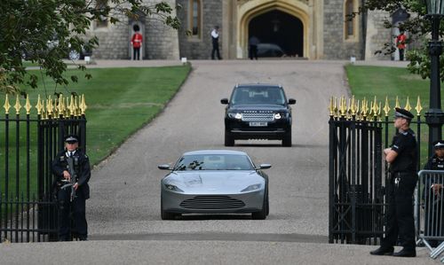 The happy couple head off toward married life through the Windsor Castle gates in the Aston Martin.