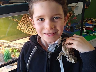 Young boy with bearded dragon on shoulder.