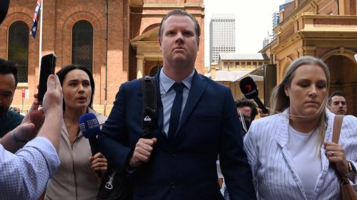 Senior Constable Christian White (centre) leaves the NSW Supreme Court in Sydney with his fiancee (right) after being found guilty by a jury of the manslaughter of 95-year-old Claire Nowland, who he electrocuted at a nursing home in Cooma . Sydney, New South Wales. November 27, 2024 Photo: Kate Geraghty