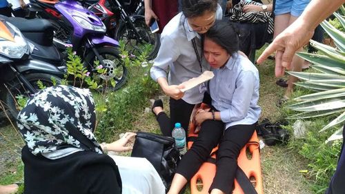 A woman on a stretcher is assisted by a companion after a powerful earthquake was felt in Davao City, Philippines.