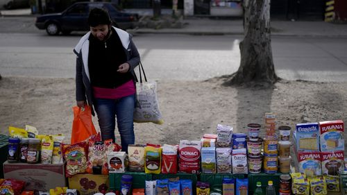 A shopper looks at food displayed in a market where customers can buy or barter.