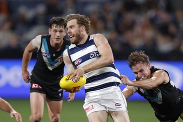 Cameron Guthrie tries to dispose of the footy in a clash between Geelong and Port Adelaide.