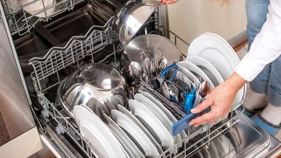 Unloading Dishwasher In The Kitchen