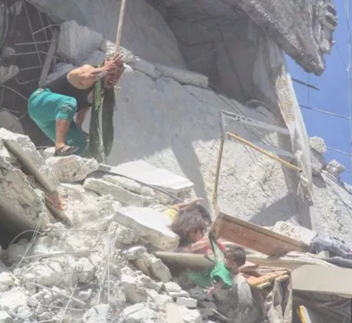 Their father looks on with horror at his two young daughters, teetering on the destroyed edge of a bombed building. One girl grabs the shirt of her infant sister, trying to save her from falling from the rubble.