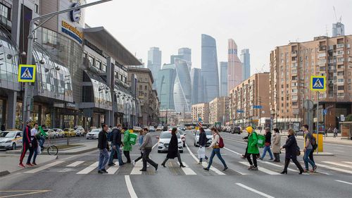 Pedestrians cross a street in front of skyscraper office buildings situated in the Moscow International Business Centre.