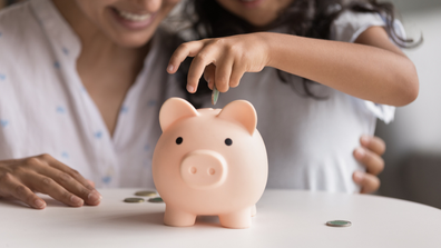 Woman and child sitting behind a piggybank