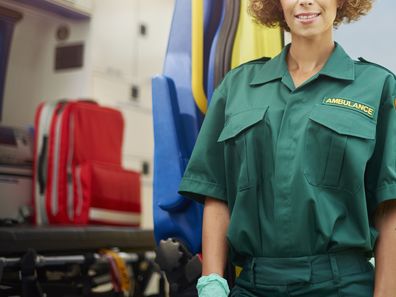 Paramedic stands next to ambulance in stock photo