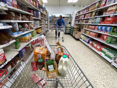 Trolley in supermarket carrying different food items.