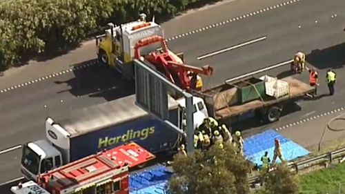 Emergency crews attempt to rescue a driver trapped in their car between two trucks. (9NEWS)