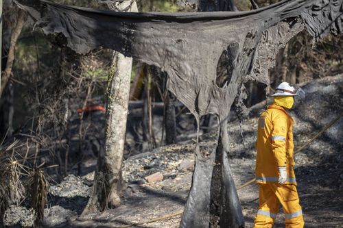 Members of the Queensland Fire Brigade put out spot fires at Binna Burra Road, Beechmont where ten homes were lost to the fires