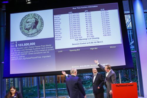 People point to the screen that shows the final price for Russian journalist Dmitry Muratov's 23-karat gold medal of the 2021 Nobel Peace Prize after being auctioned at the Times Center, Monday, June 20, 2022, in New York. 