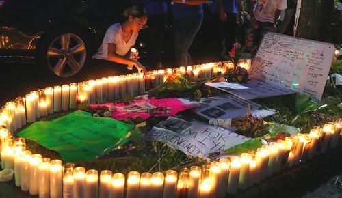 A woman adjusts candles during a vigil for Miya Marcano at Arden Villas